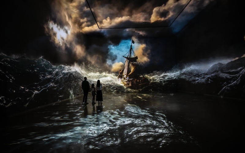 Gallery 3 people standing in front of painting of sea and ship